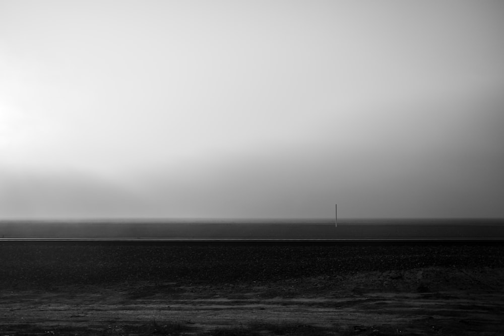 grayscale photo of a person standing on a beach