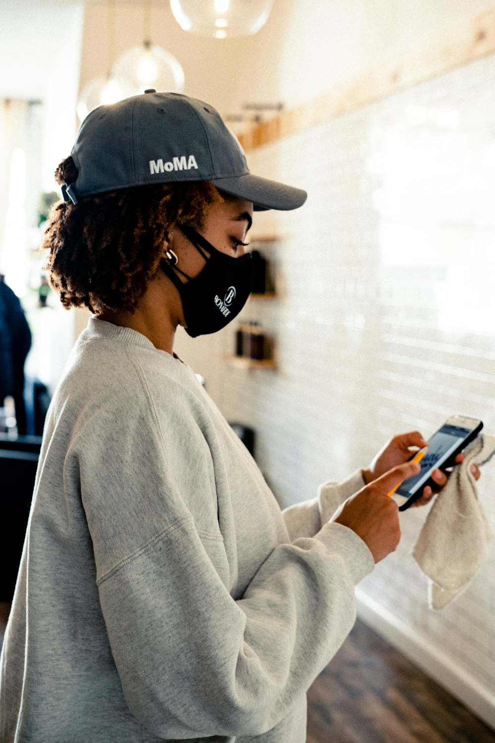 woman in gray sweater holding smartphone