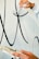 A person is painting large black calligraphic strokes on a light-colored wall. The hand holding the brush is steady and focused on creating smooth, flowing lines, while the other hand appears to be holding a palette.