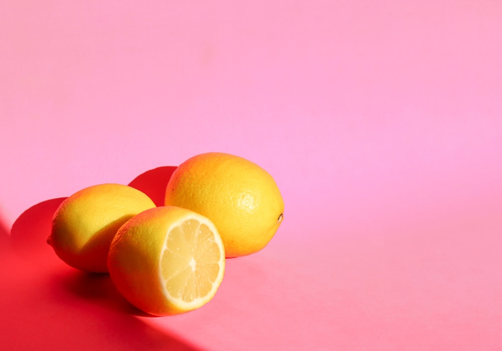 3 lemon fruits on pink surface