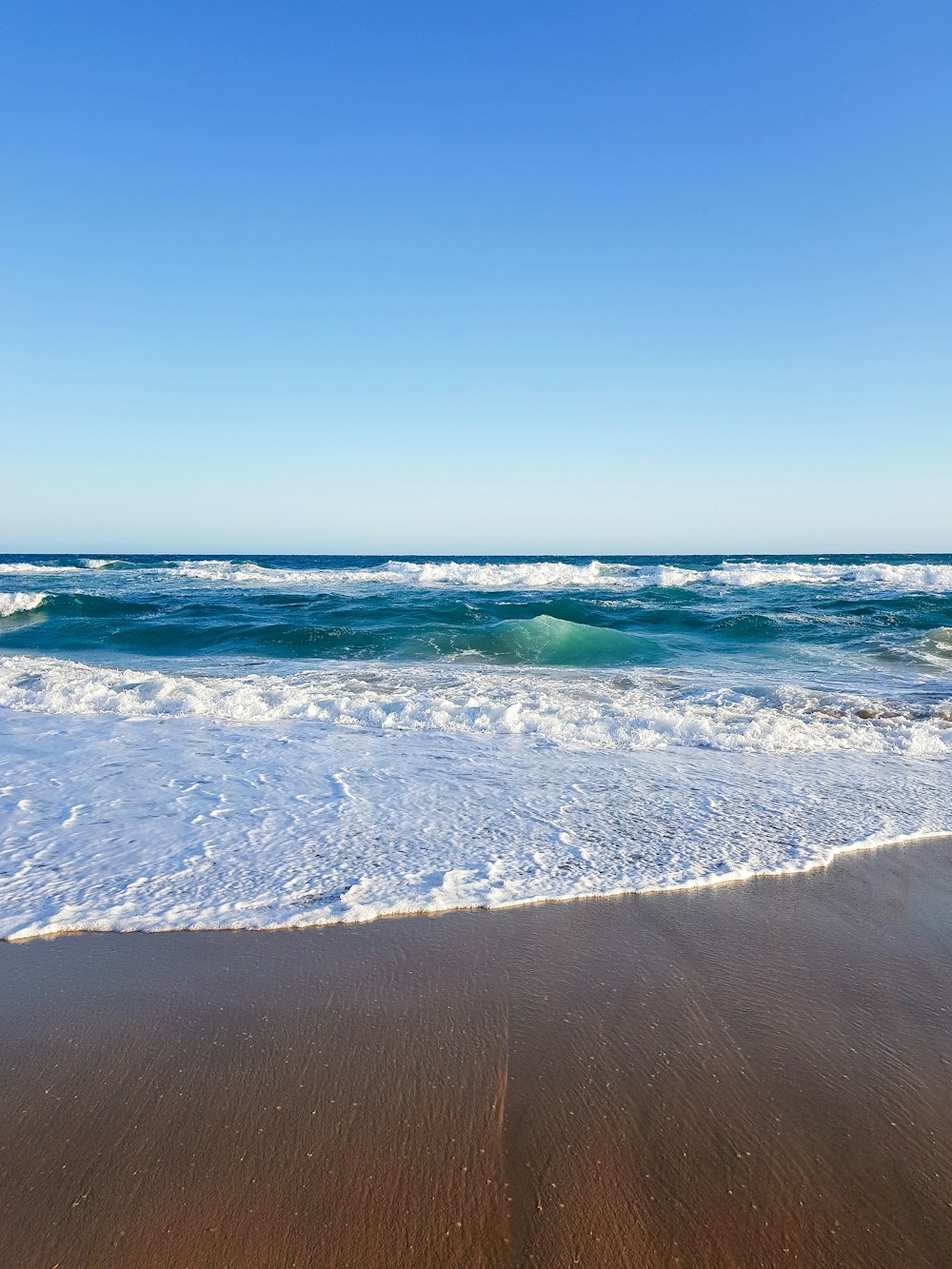 ocean waves crashing on shore during daytime