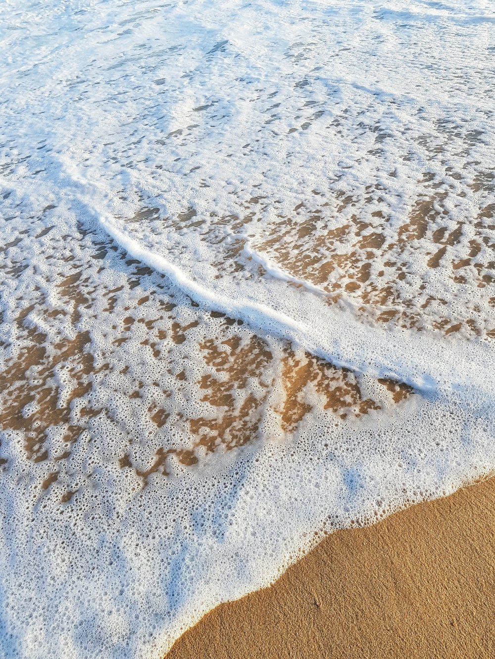 a wave coming in to the shore of a beach