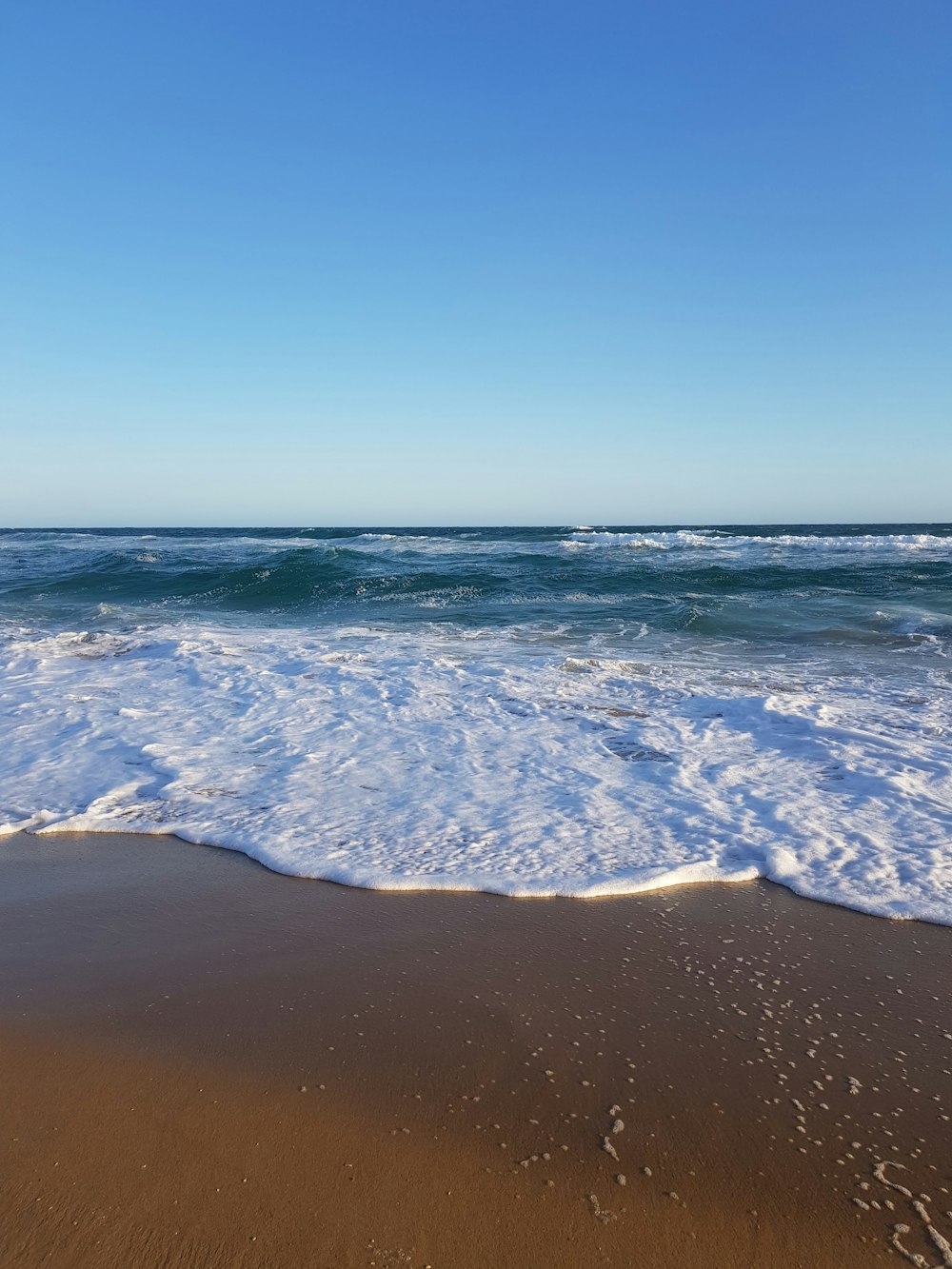 sea waves crashing on shore during daytime