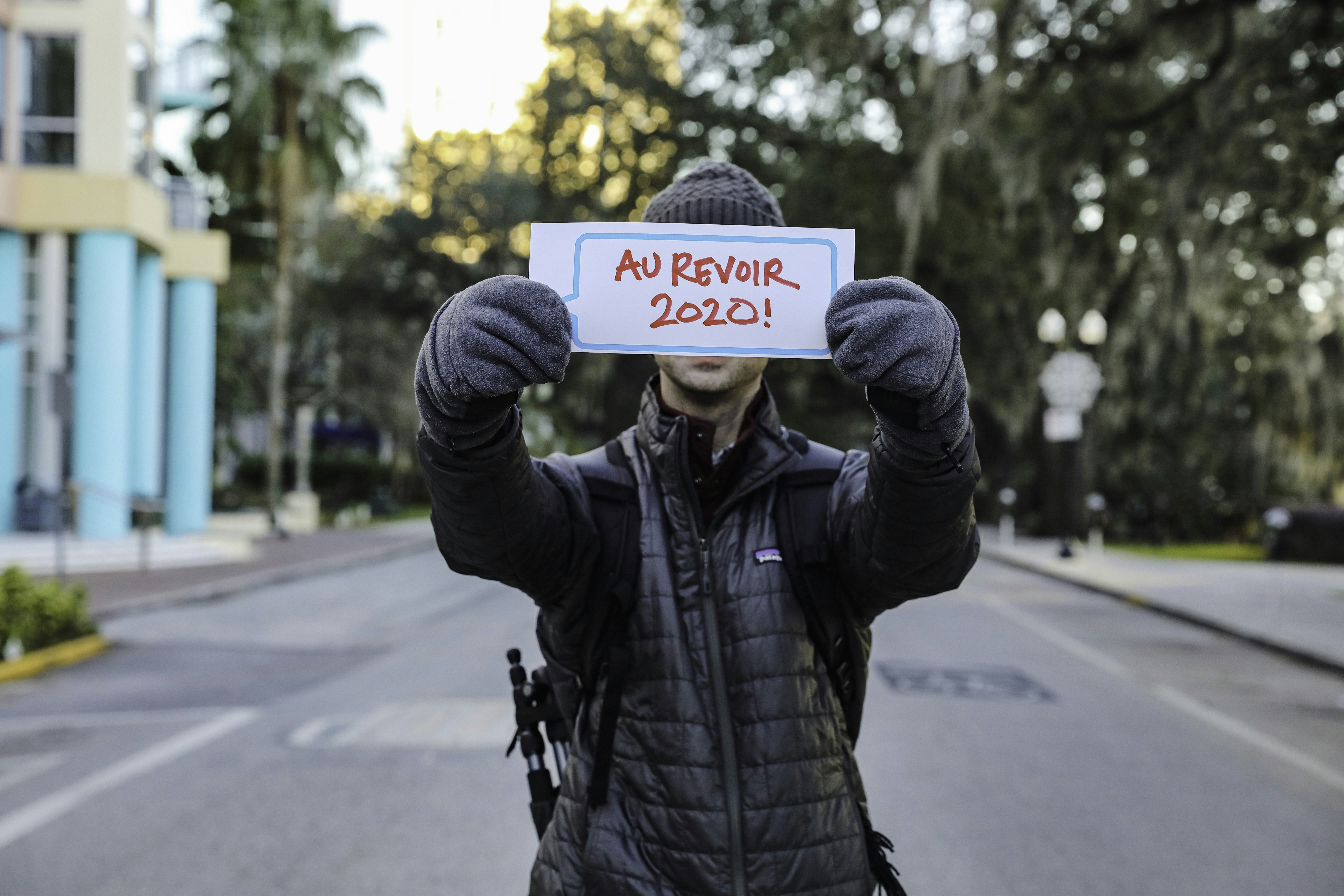 man in black leather jacket holding white and black sign