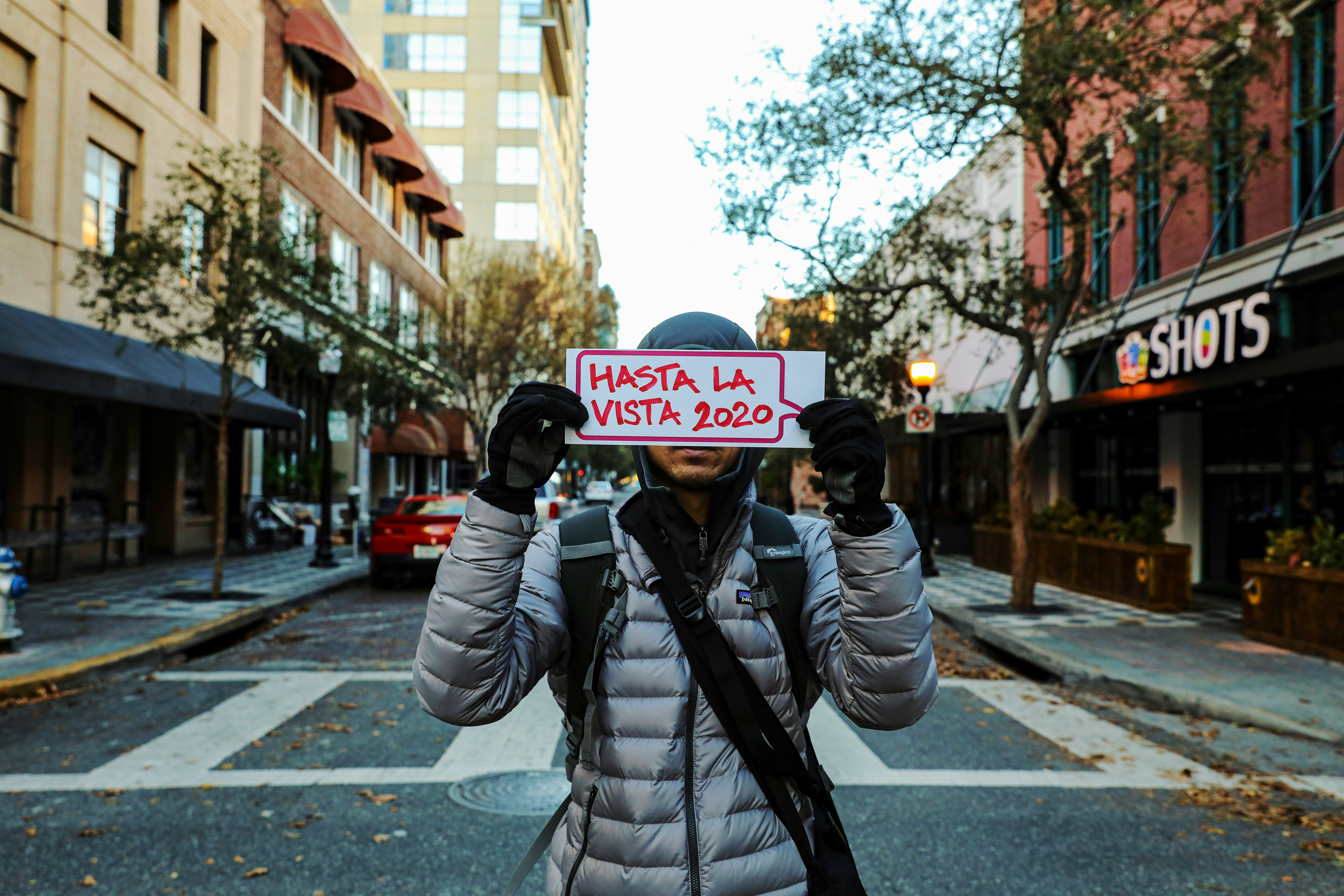 woman in black and white jacket taking photo of road during daytime