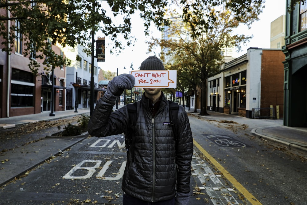 man in black leather jacket standing on pedestrian lane during daytime