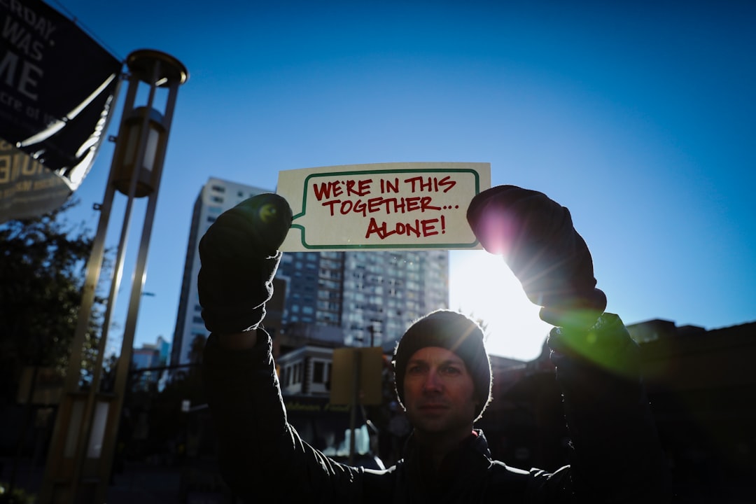 woman in black long sleeve shirt holding green and white signage