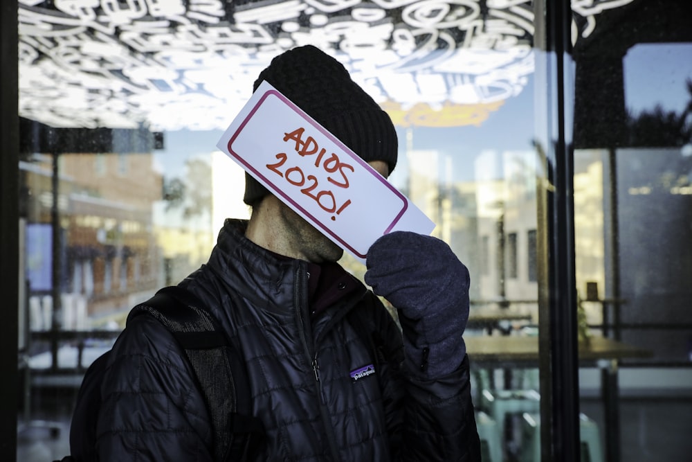 person in black jacket holding white and red card