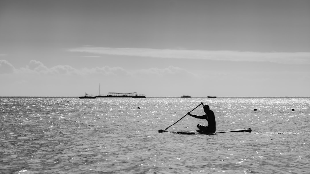 grayscale photo of man riding on boat on sea