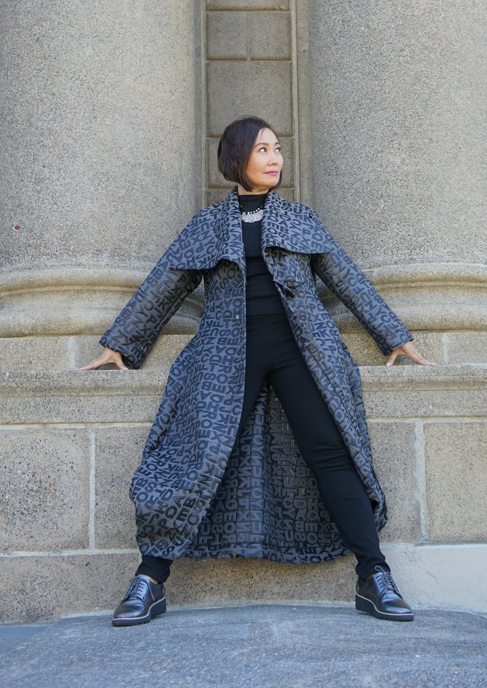 woman in blue coat and black skirt sitting on gray concrete stairs