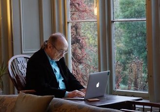 man in black suit jacket using macbook