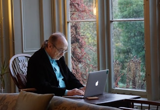 man in black suit jacket using macbook