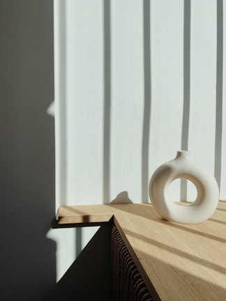 Close-up of a stylish ceramic vase on a wooden table with natural light.