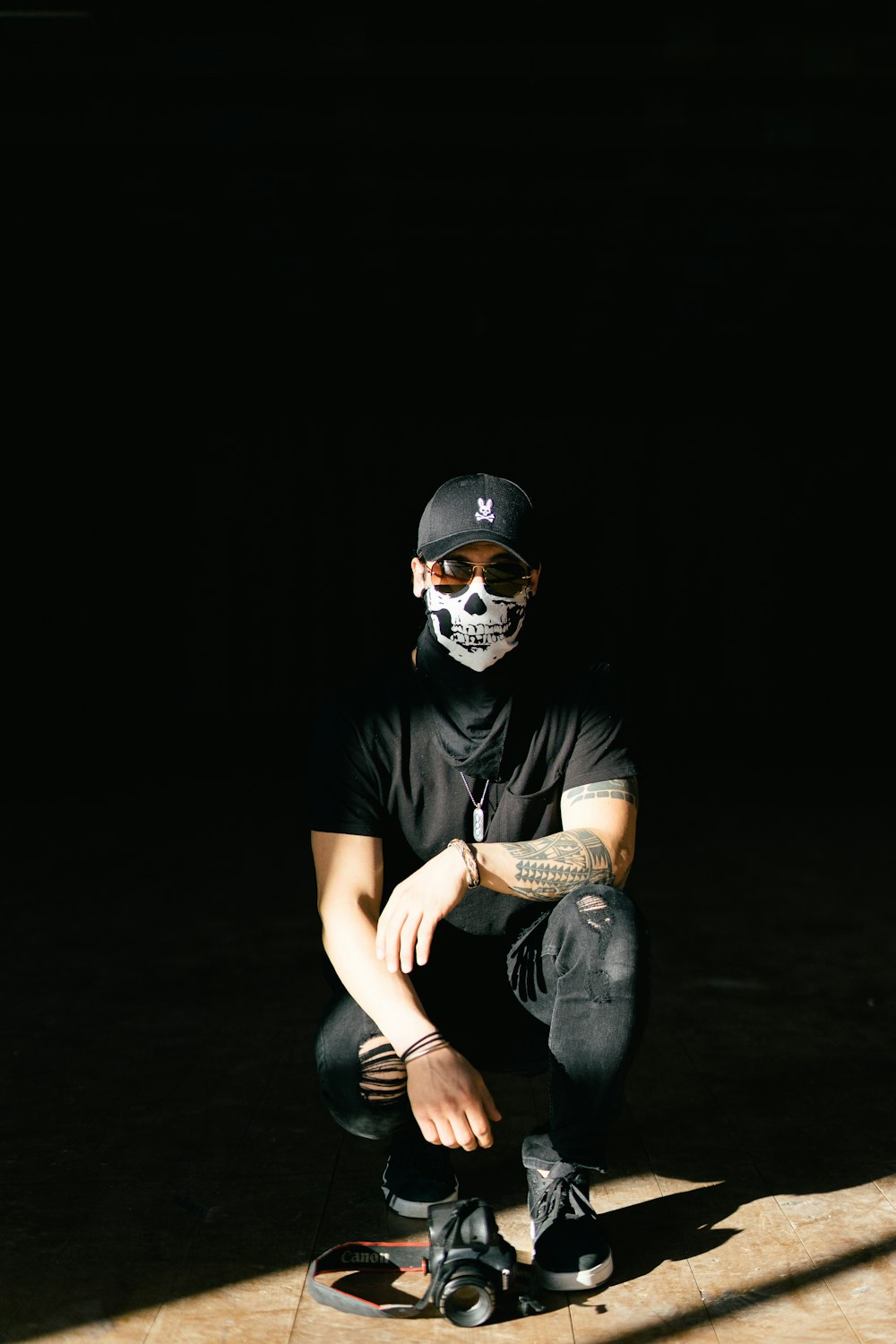 man in black crew neck t-shirt and blue denim jeans wearing white mask
