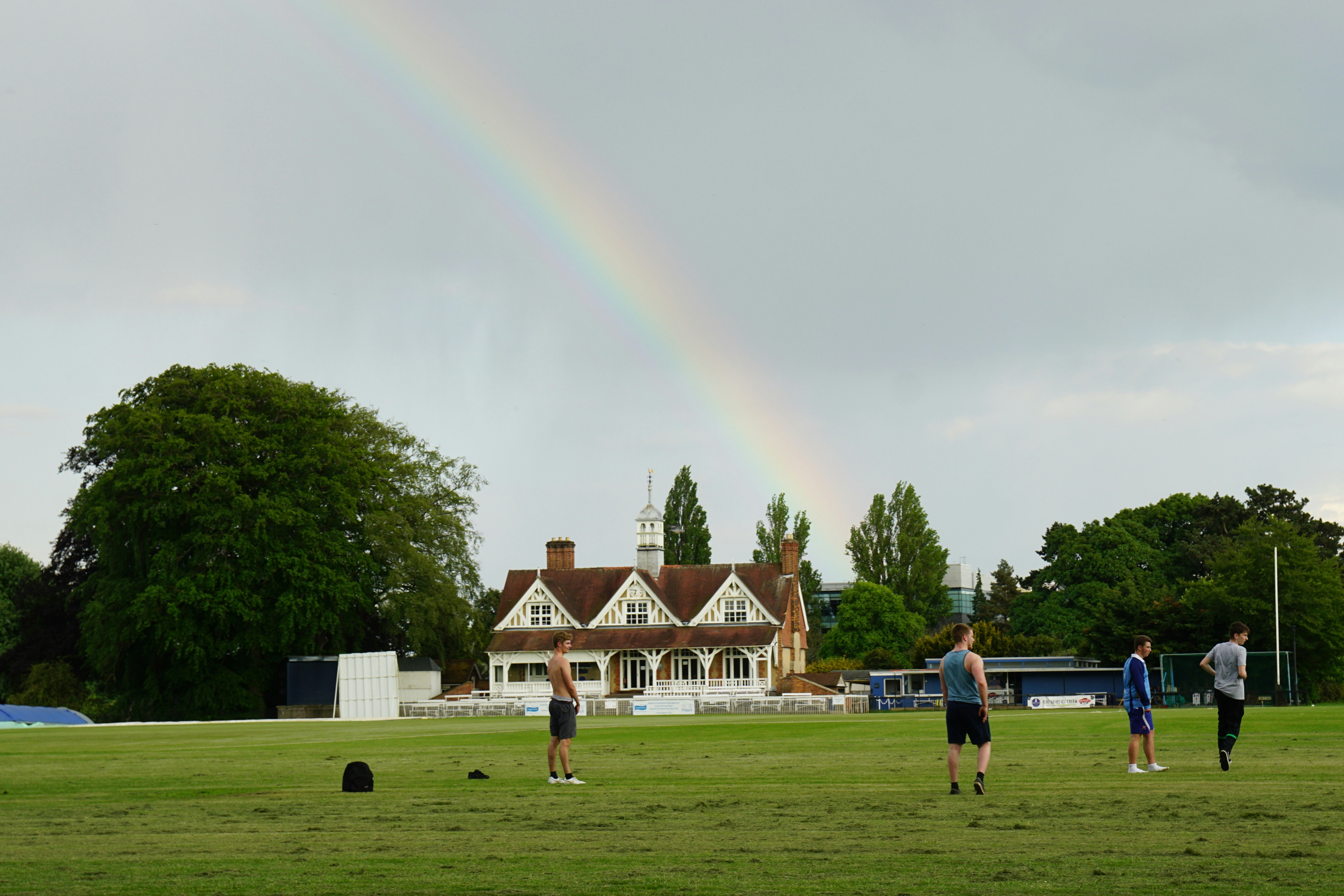 people standing on green grass field near brown and white house during daytime