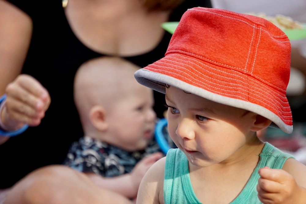 baby in orange hat and blue tank top