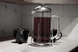 Elegant French press with freshly brewed coffee on a wooden countertop with aguamarina accents.