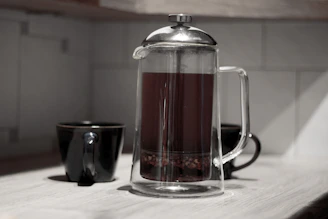 Rustic industrial scene showing a French press on a concrete countertop with soft shadows.