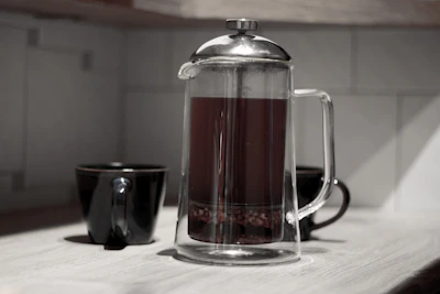 Rustic industrial scene showing a French press on a concrete countertop with soft shadows.