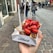 Close-up of a happy customer holding a golden Belgian waffle topped with strawberries and chocolate drizzle, with a sky blue and cloud-themed food truck in the background.