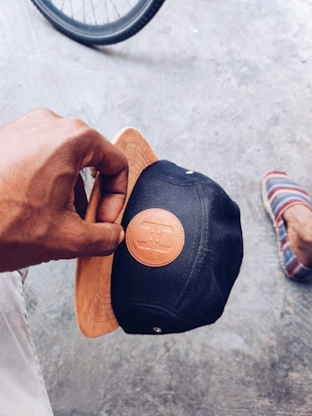 Close-up of a slyp branded snapback hat resting on a concrete ledge beside a skateboard.