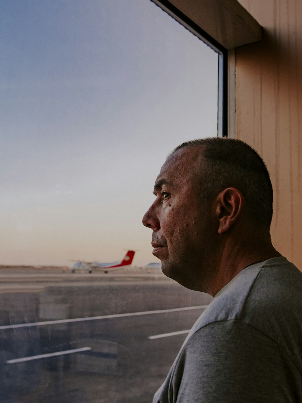 man in gray collared shirt standing near window during daytime