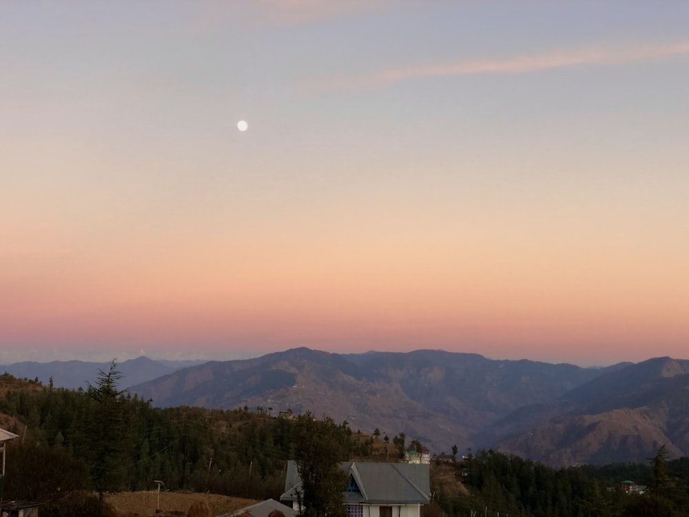 white and brown house near green trees and mountains during daytime