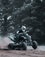 A rider speeding through a dusty ATV trail surrounded by tall trees at Mainland Shores.