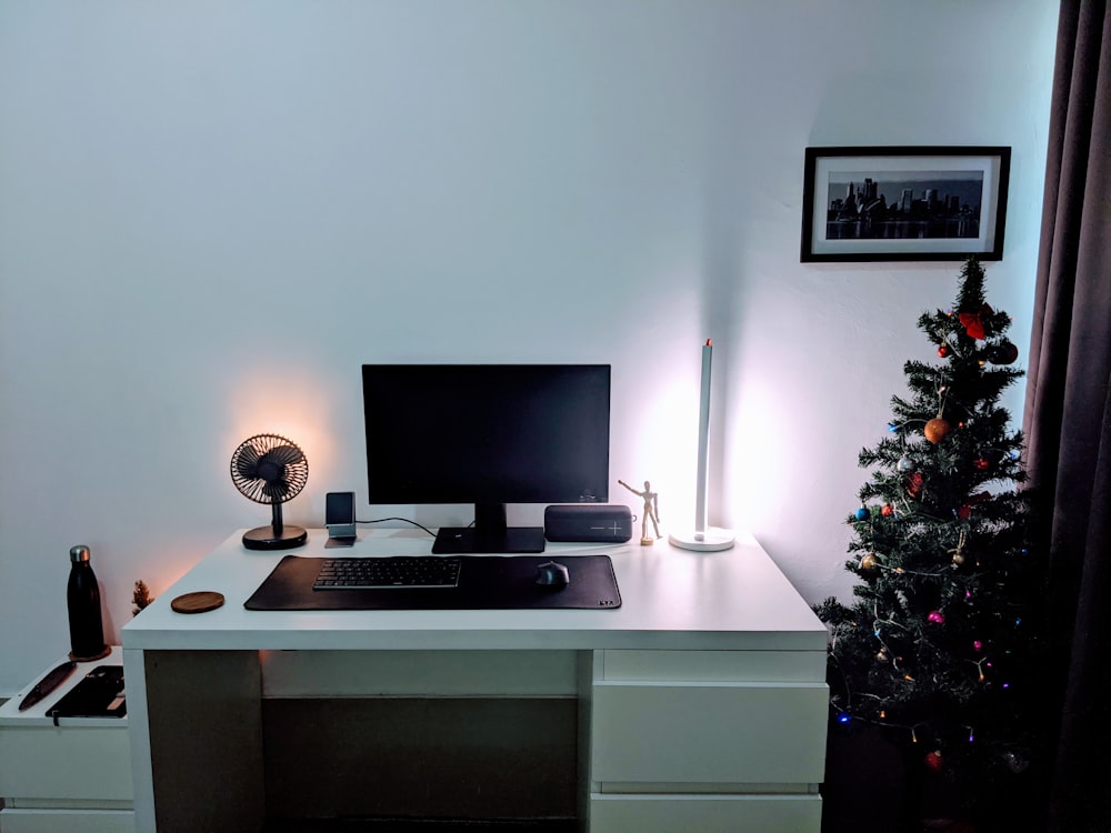 a desk with a computer and a christmas tree
