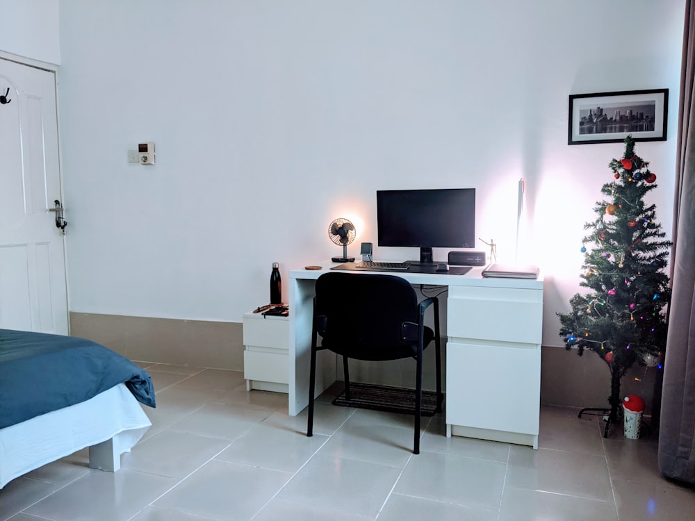 a bedroom with a desk, computer and a christmas tree