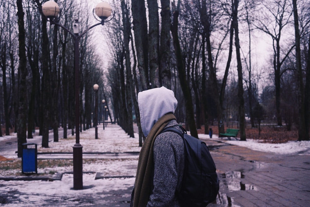 person in black jacket and white knit cap standing on sidewalk during daytime