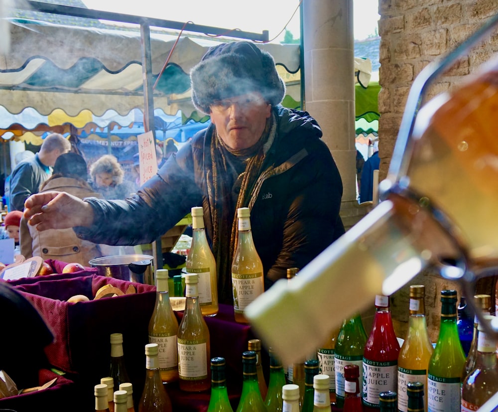 man in brown jacket holding clear glass bottle