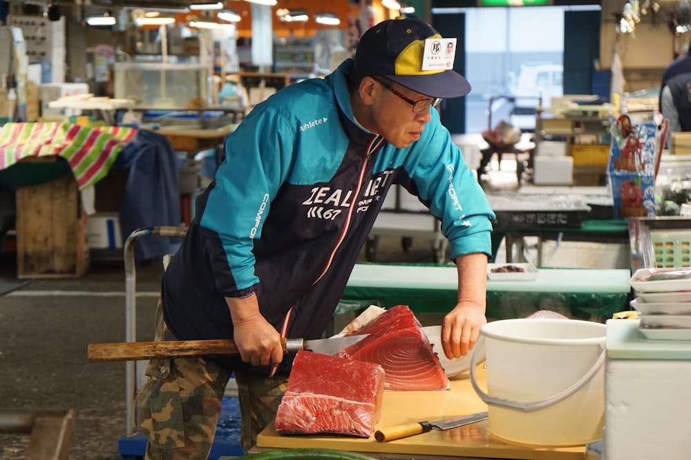 man in blue and white jacket holding raw meat