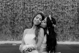 grayscale photo of woman in wedding dress beside woman in wedding dress