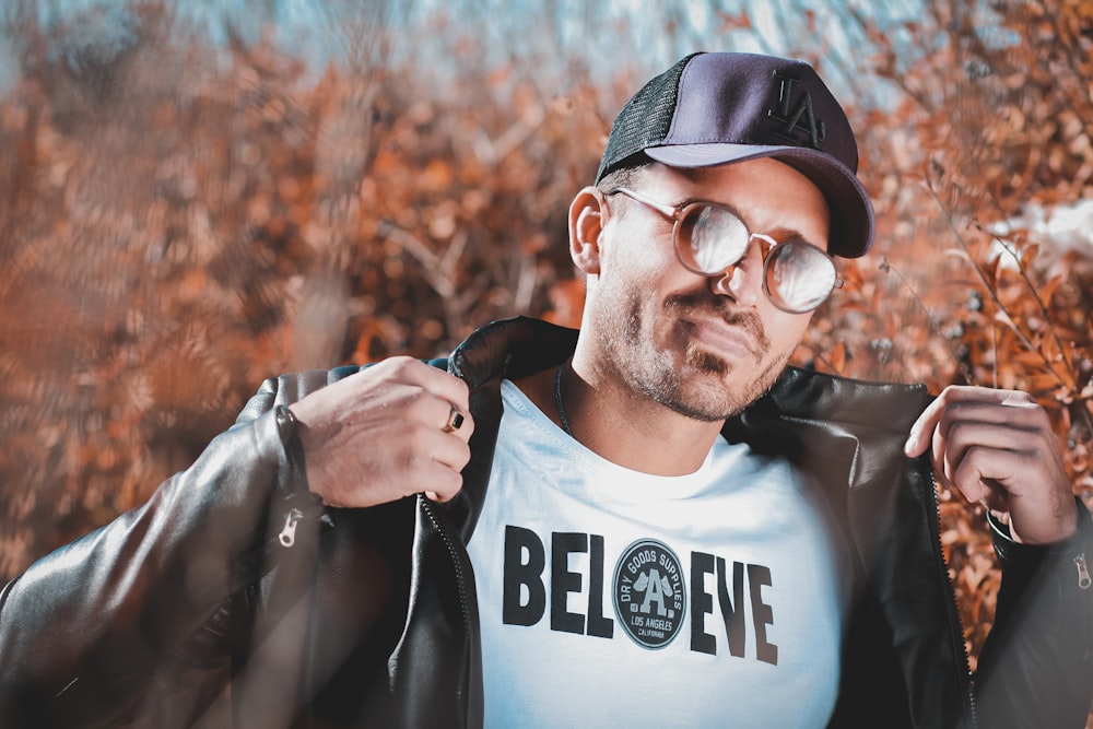 man in black and white crew neck shirt wearing black cap and sunglasses