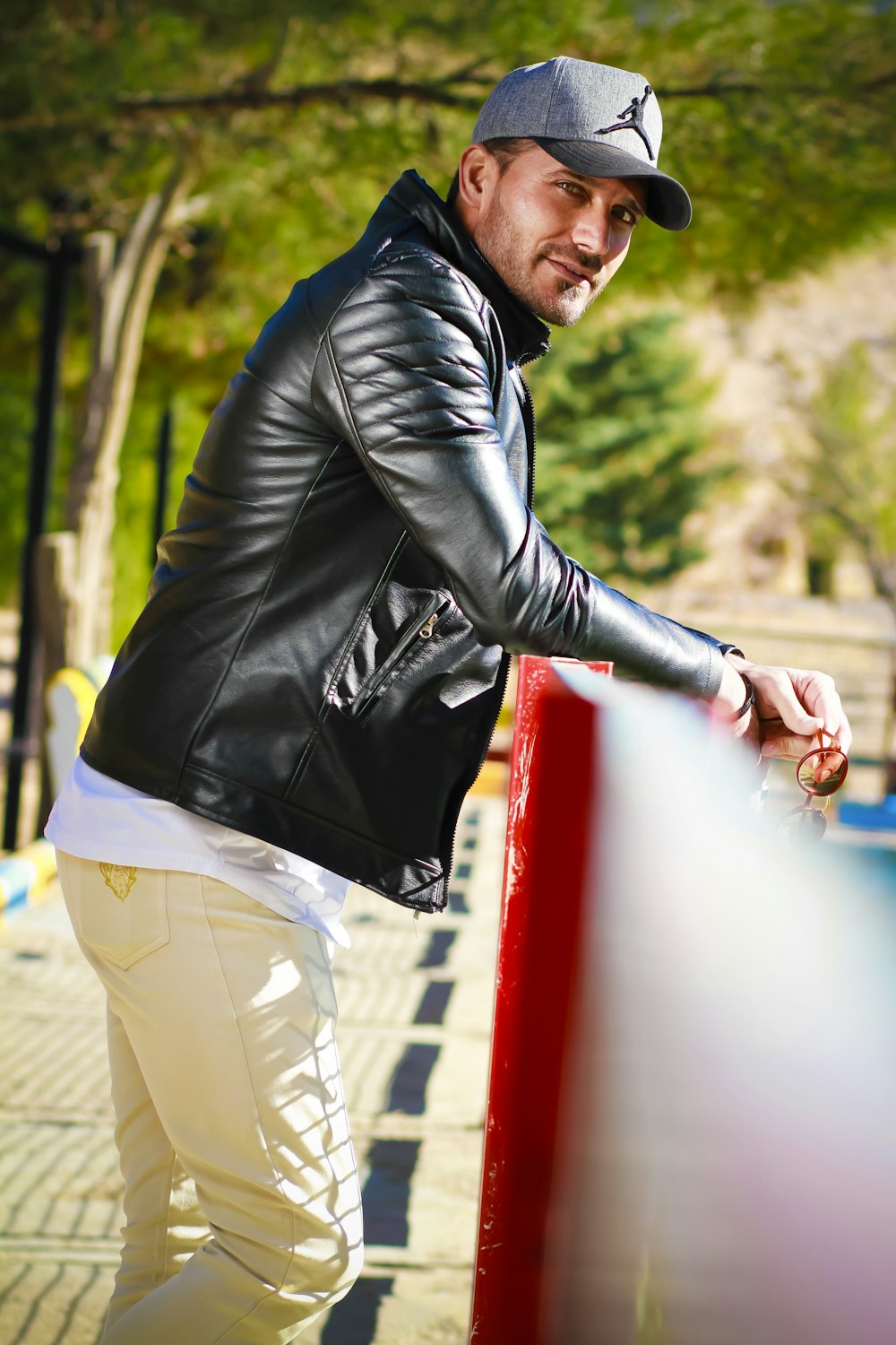 man in black leather jacket and beige pants