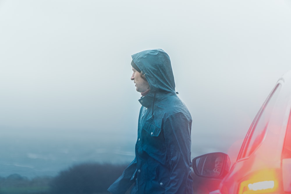 man in blue hoodie standing on top of mountain during daytime