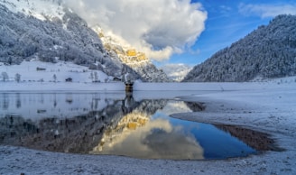 snow covered mountain near body of water during daytime