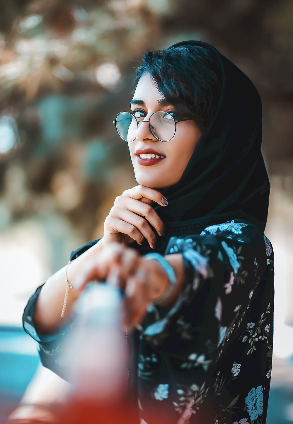 Frau in schwarzem Hijab und blau-weißem geblümtem Langarmhemd