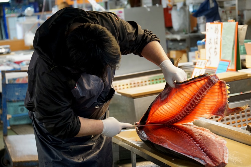 person in black long sleeve shirt holding brown and white fish