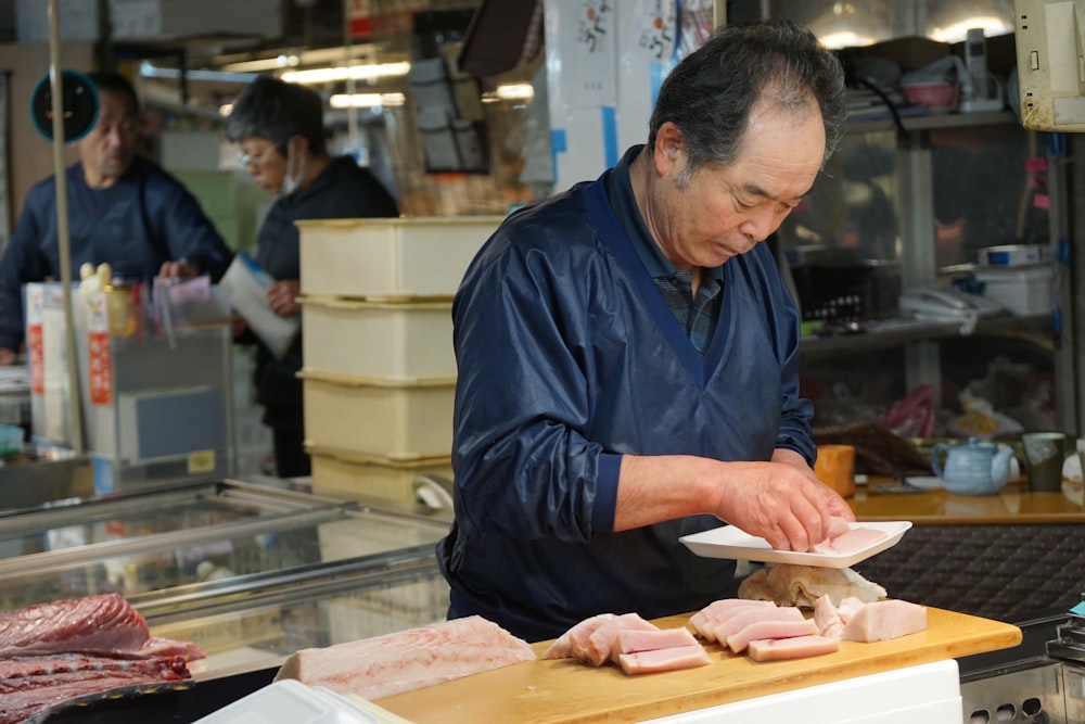 man in blue jacket slicing meat