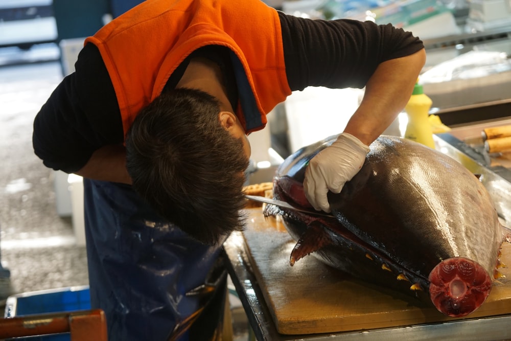 man in orange t-shirt and black pants holding black fish