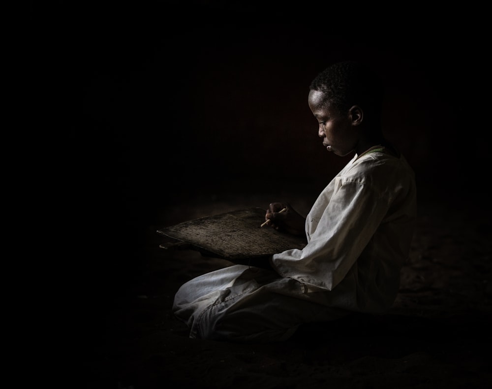 man in white robe sitting on ground