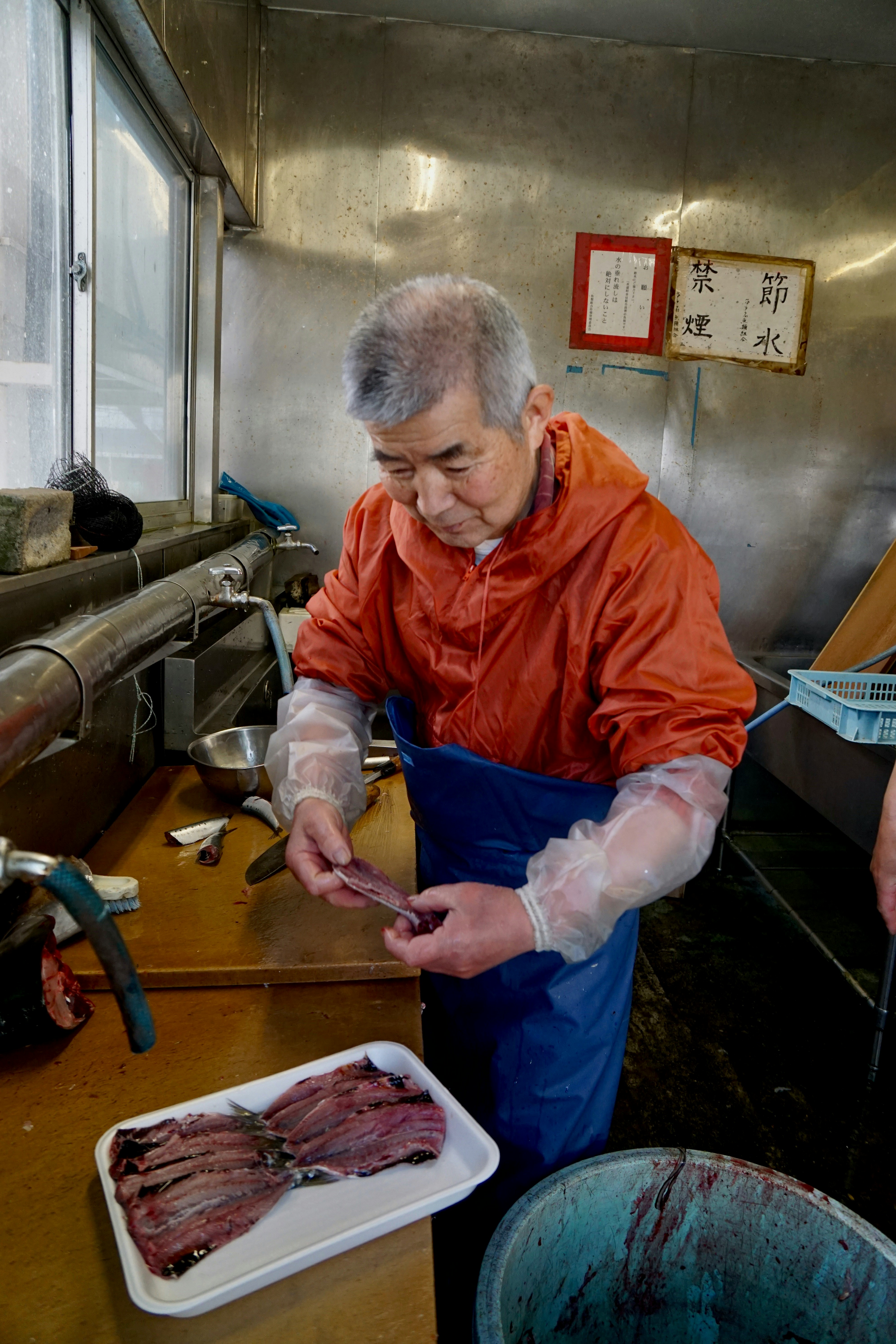 man in orange jacket holding white plastic gloves