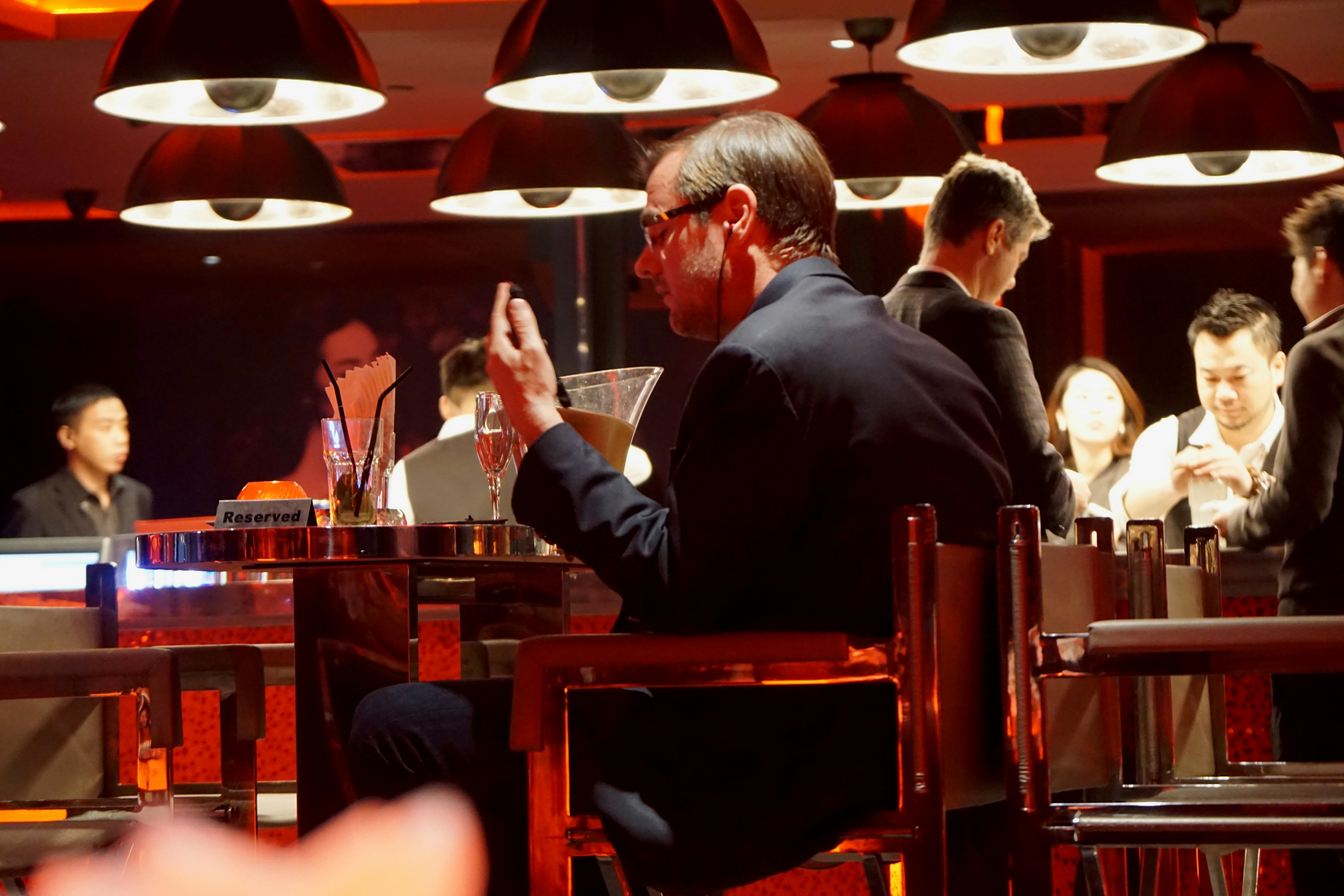 man in black suit sitting on brown wooden chair