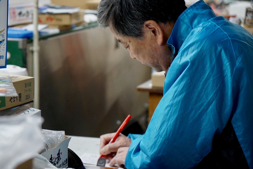man in blue dress shirt writing on white paper