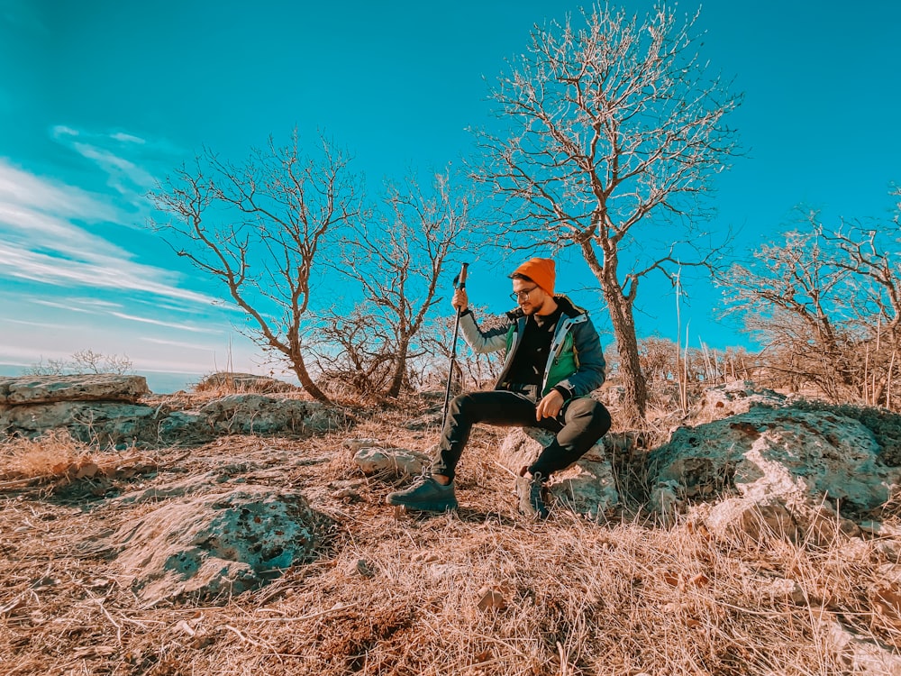 woman in black jacket and black pants sitting on brown rock during daytime