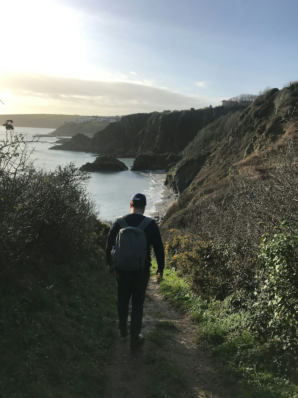 man in black jacket standing on cliff near body of water during daytime