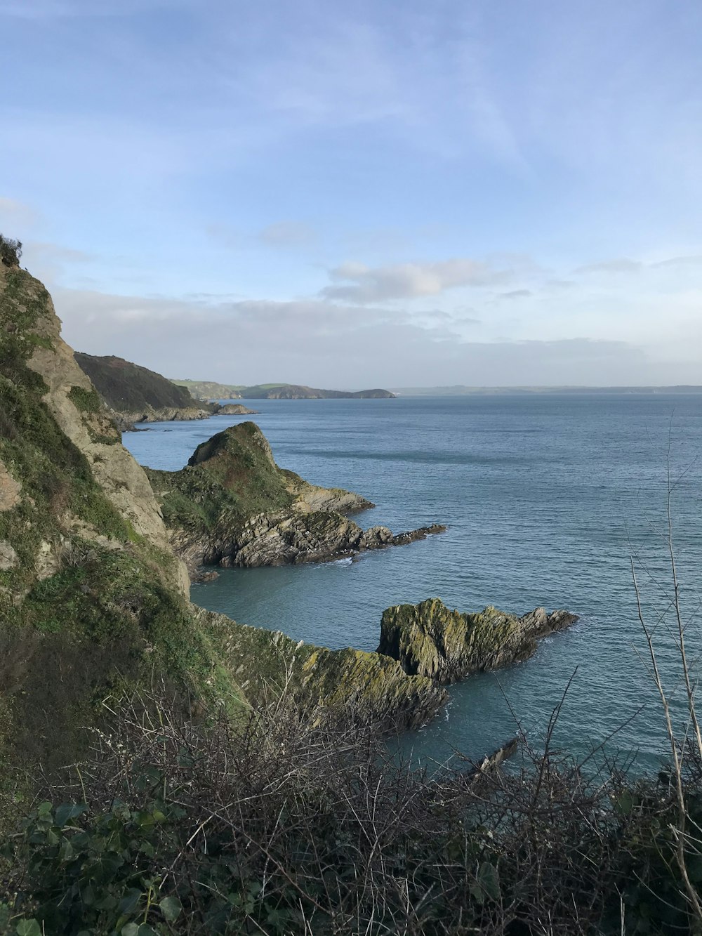 brown and green rock formation beside body of water during daytime