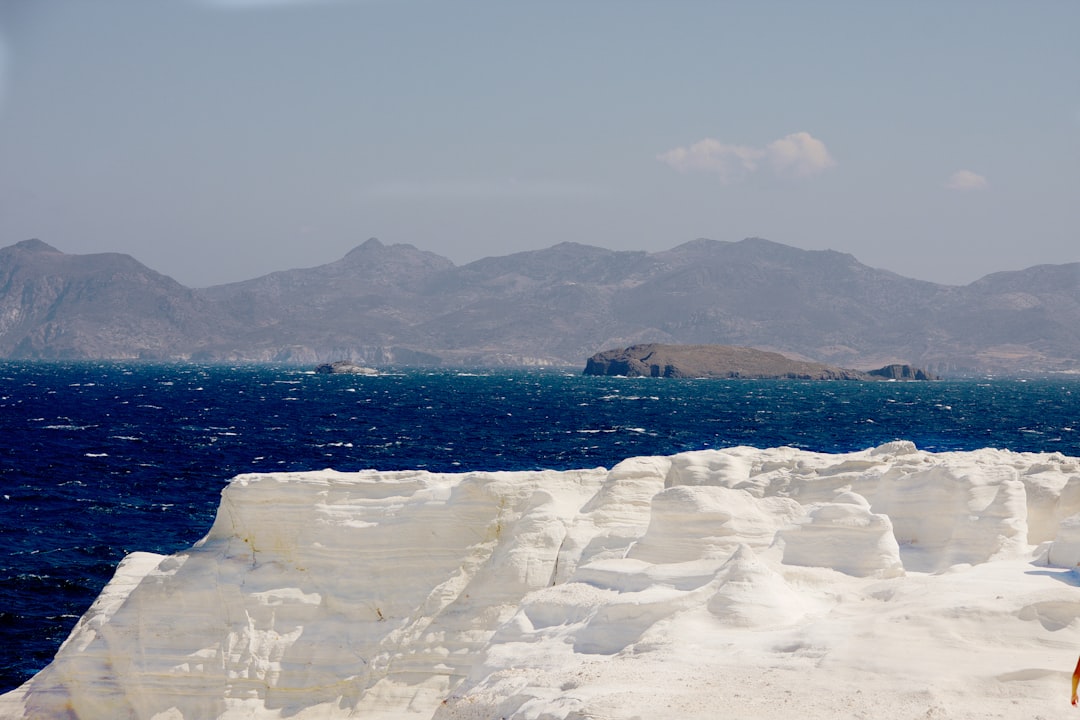 white ice on white rock near body of water during daytime